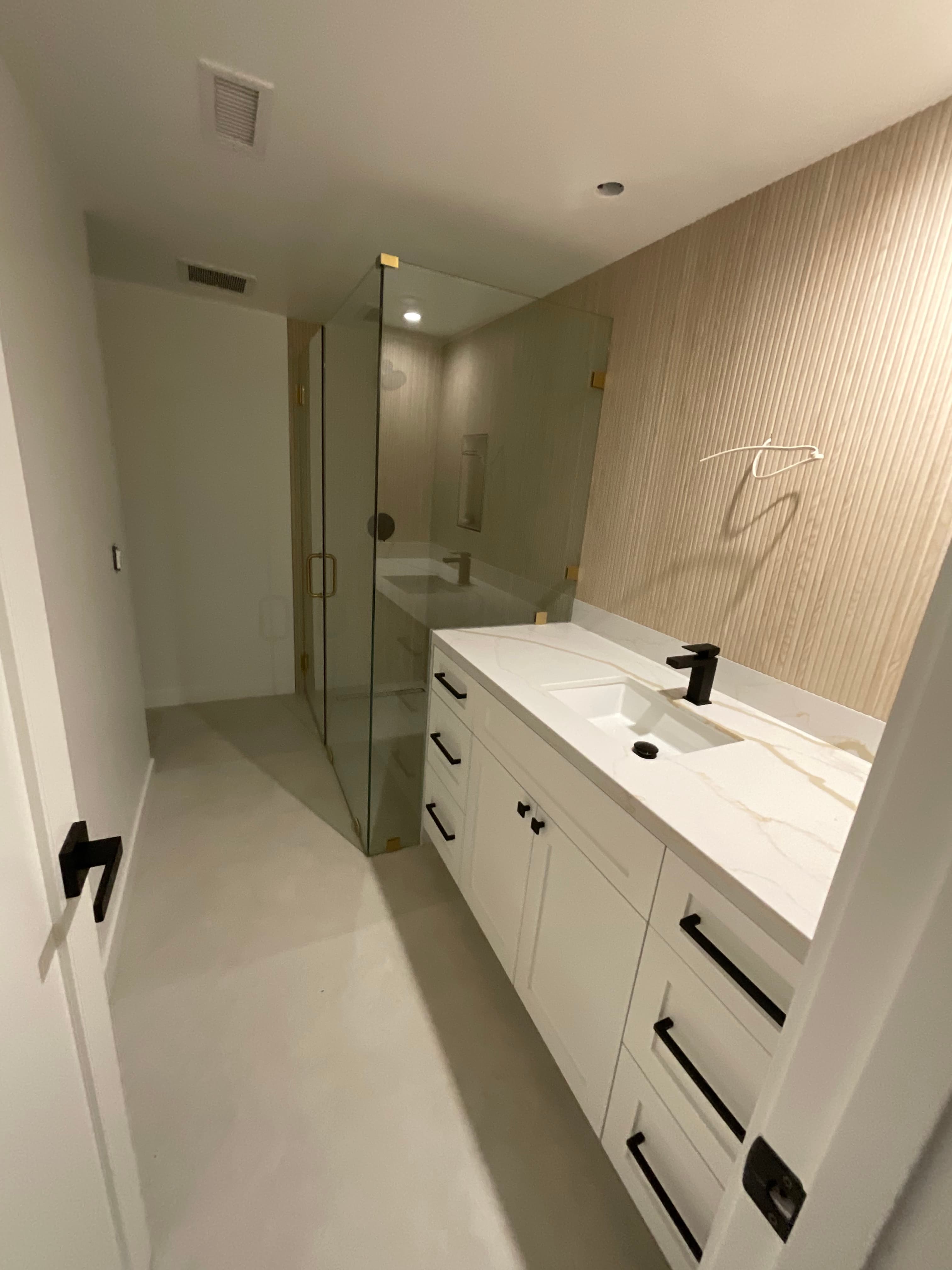 Modern bathroom featuring a white vanity with black hardware and a glass-enclosed shower.