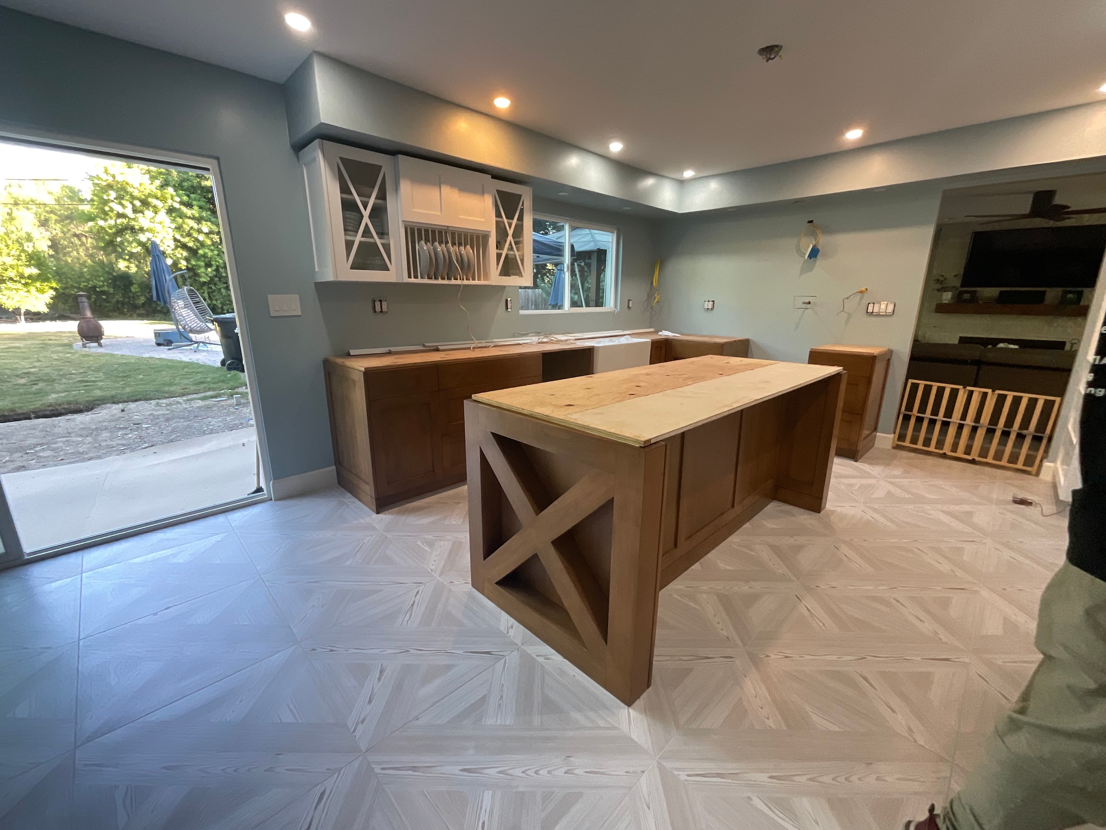 Unfinished kitchen with wooden island, light blue walls, and geometric patterned tile flooring.