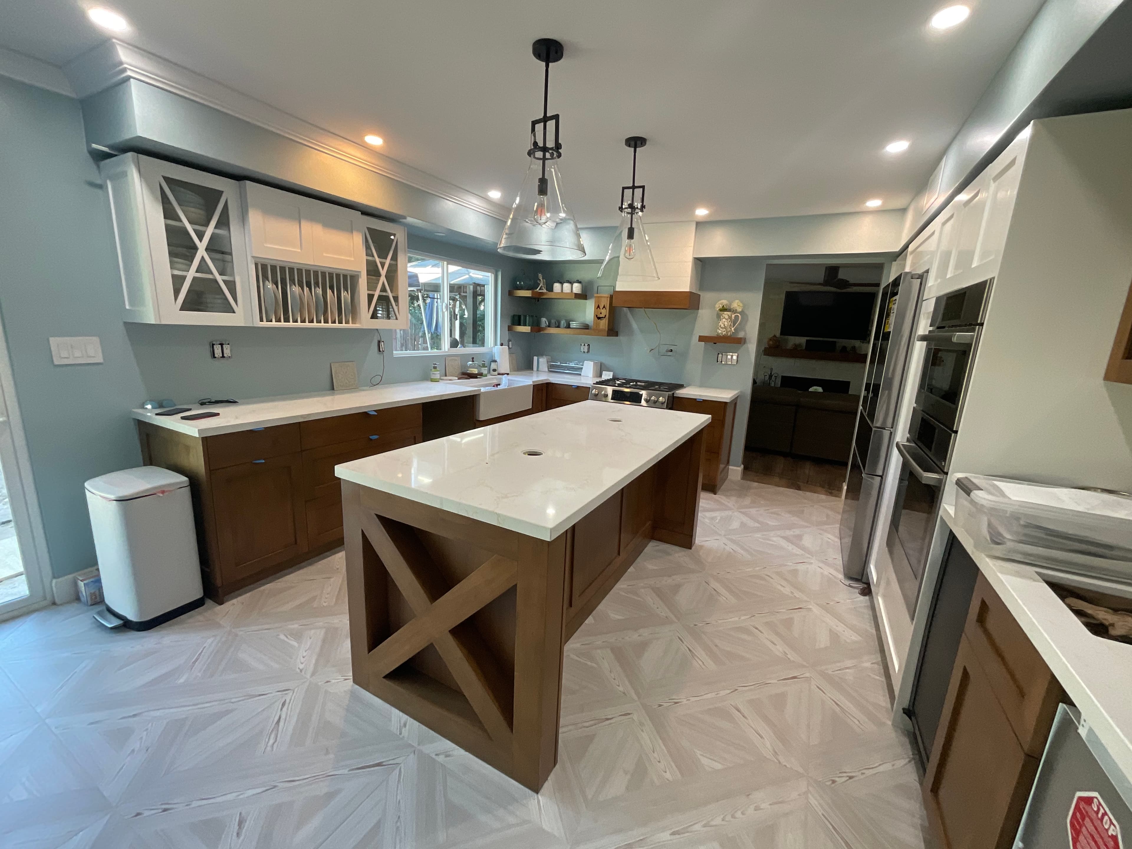 Modern kitchen featuring a large wooden island, white countertops, blue walls, and patterned tile flooring.